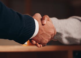 Two hands shaking in a professional setting, symbolizing business deal or agreement.